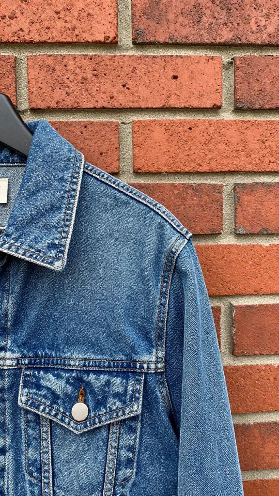 denim jacket collar against red brick wall