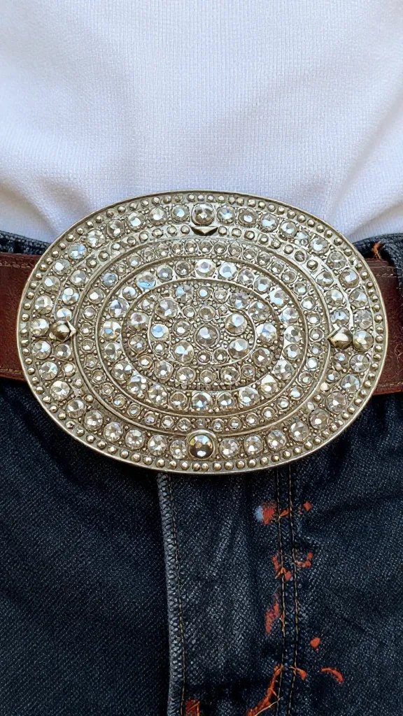 closeup rhinestone western belt buckle on worn leather